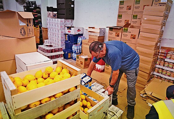 Un voluntario recoge cajas de fruta para el reparto del Banco de Alimentos.
