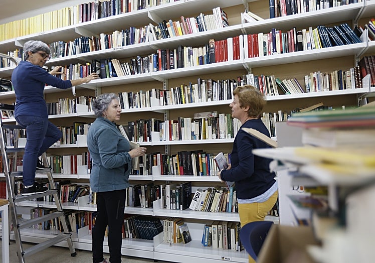 Voluntarias de la biblioteca popular de Pizarrales colocando libros.