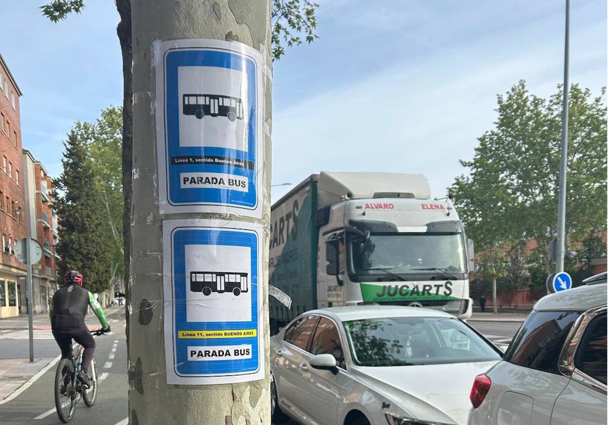 Los carteles anunciando las paradas en las líneas 1 y 11, pegados en un árbol en la avenida de Los Cipreses.