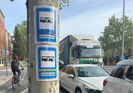 Los carteles anunciando las paradas en las líneas 1 y 11, pegados en un árbol en la avenida de Los Cipreses.