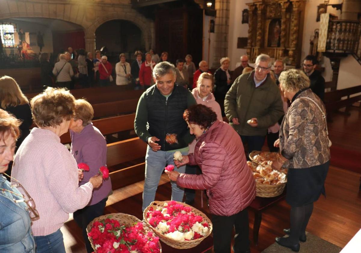 Imagen de los fieles recogiendo las flores y los bollos tras la misa en la iglesia de Santa María.