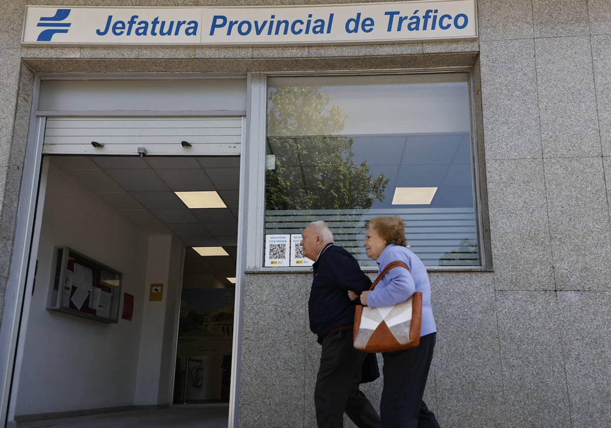 Dos personas mayores pasan junto a la Jefatura Provincial de Tráfico.