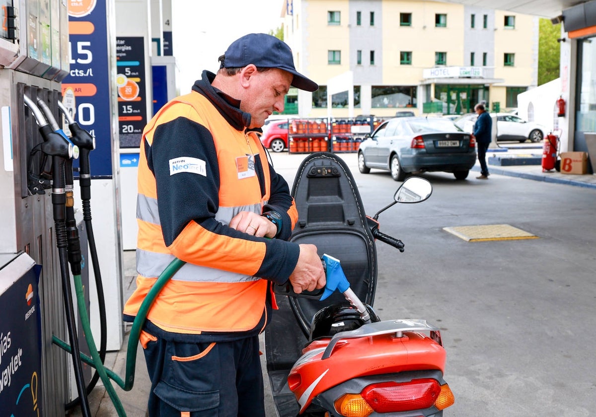 Trabajador de una estación de servicio llena el depósito de una moto.