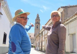 Los vecinos de Palaciosrubios, Quico Albarrán Vaquero y Clara María Vaquero, señalan la torre de la iglesia desde una céntrica calle de la localidad.