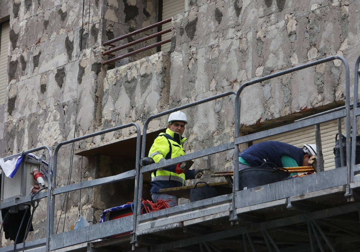 Dos trabajadores de la construcción en un andamio.