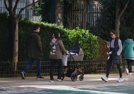 Una pareja pasea junto a su bebé por un parque de Salamanca.