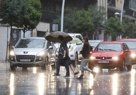 Varios salmantinos cruzan un paso de peatones con lluvia.