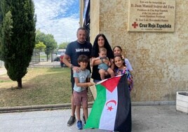 Lamina, de 10 años, posa junto a su familia y la bandera de su país.