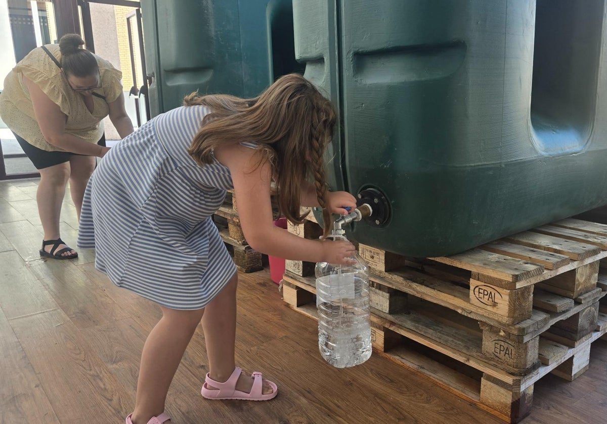 Dos mujeres cogen agua potable gratis en los depósitos instalados en Ledesma.