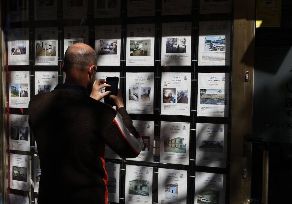 Un hombre saca una fotografía de las oferta de una inmobiliaria.