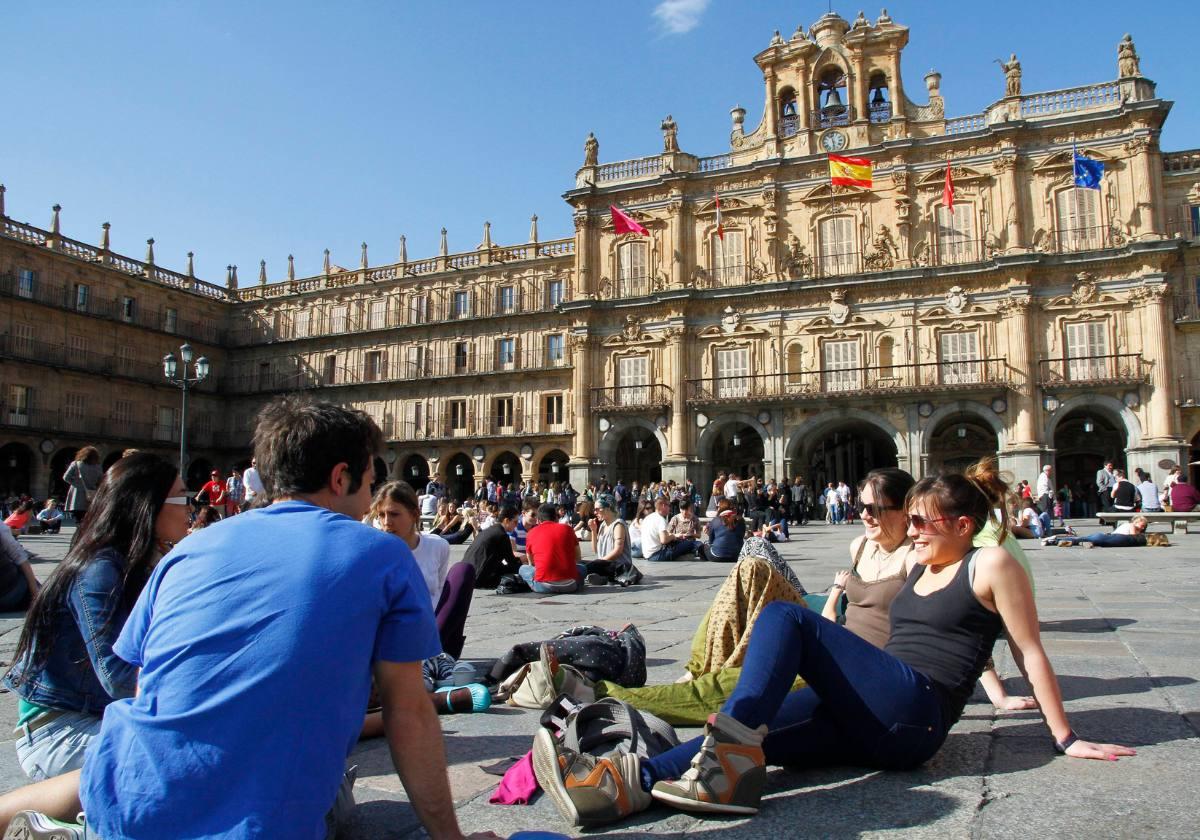 Varios jóvenes disfrutan del sol en la Plaza Mayor.