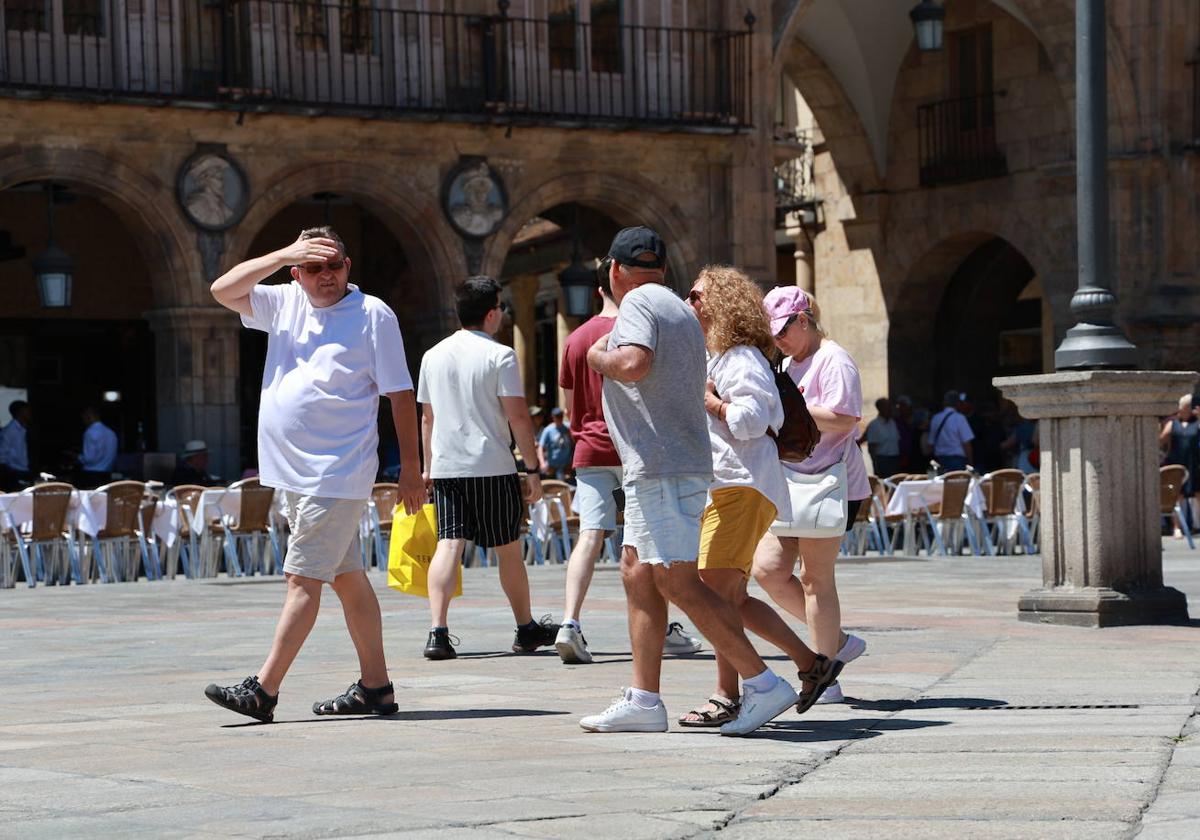 Un grupo de turistas pasea por la Plaza Mayor de Salamanca en un día caluroso.