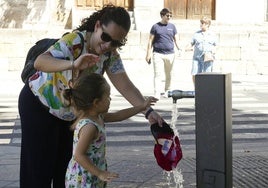 Madre e hija se refrescan en una fuente de la capital.