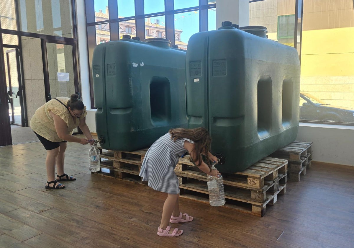 Dos vecinas de Ledesma recogiendo agua potable de los bidones instalados en el multiusos.