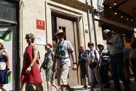 Un grupo de turistas pasa frente a la puerta de un edificio de viviendas turísticas.