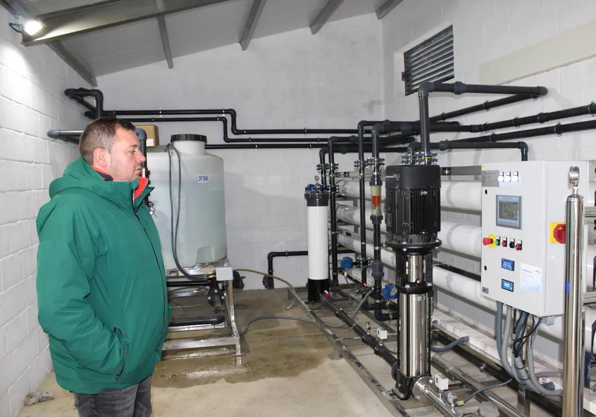 El alcalde de Villoria observa el interior de la planta de ósmosis junto al depósito de agua.