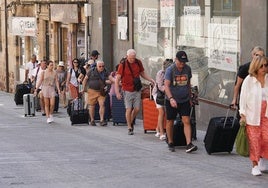 Turistas con maletas por la calle Correhuela.