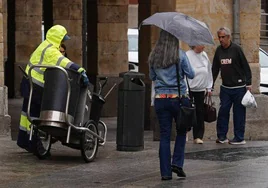 Varias personas refugiándose de la lluvia en Salamanca.