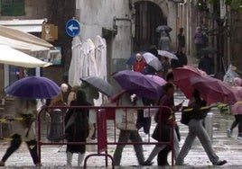 Ciudadanos se protegen con paraguas de la la lluvia.