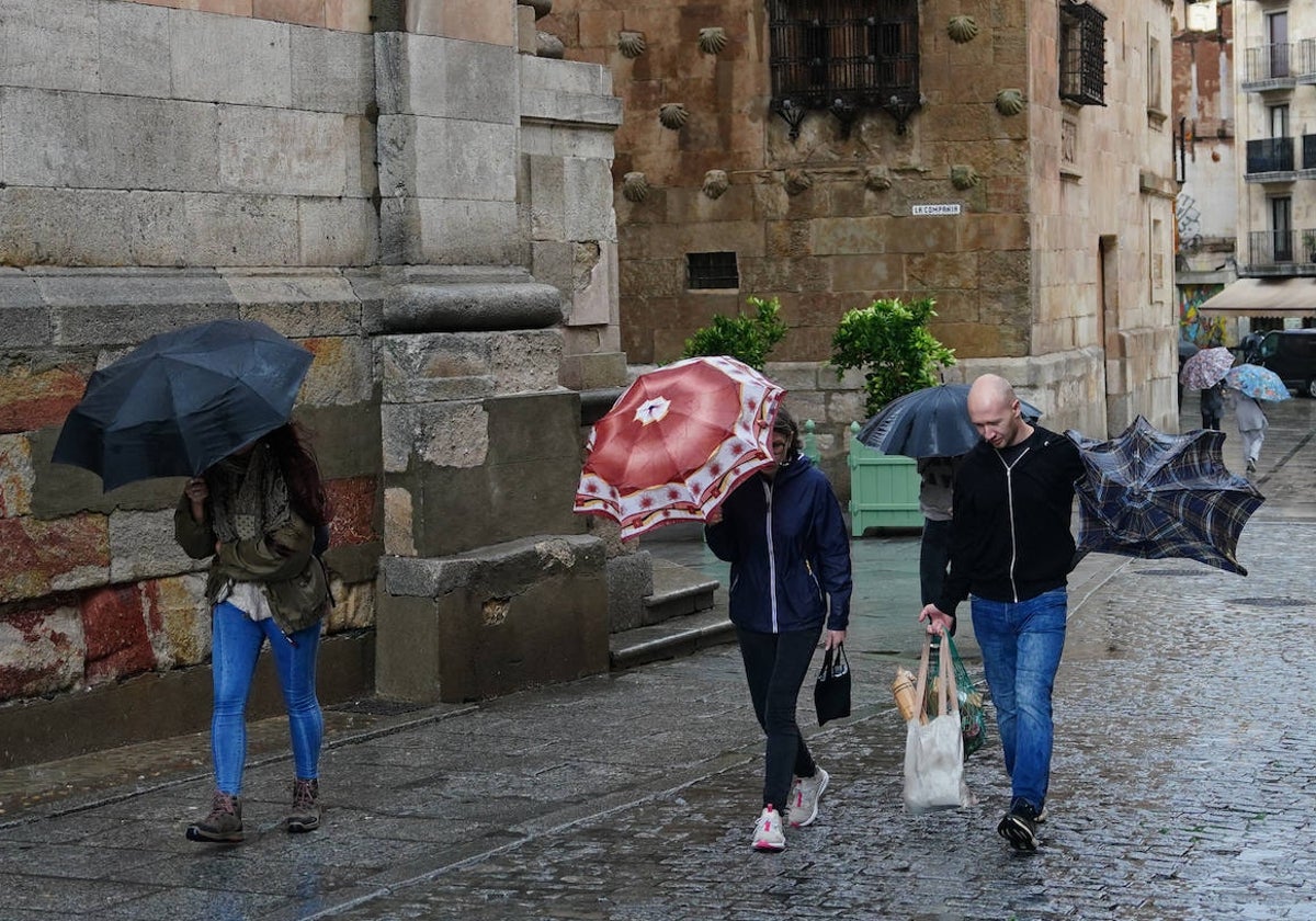 Dos visitantes sufren el frío y la lluvia en el centro de Salamanca.