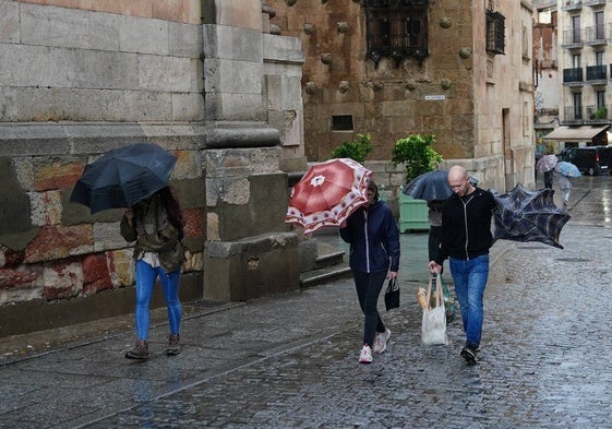 Dos visitantes sufren el frío y la lluvia en el centro de Salamanca.