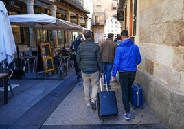 Dos turistas con maletas pasean por el centro de Salamanca.