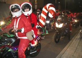 Una pareja de participantes en la papanoela motera de Santa Marta de Tormes con su moto ambientada en la Navidad