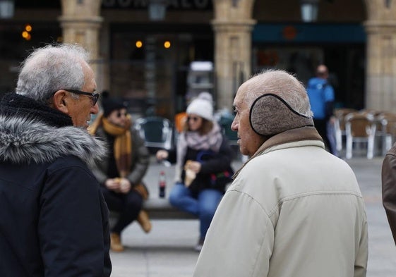 Dos salmantinos se protegen del frío en la Plaza Mayor.