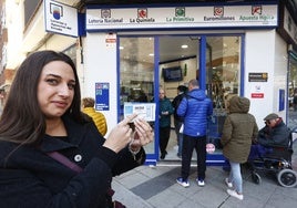 Una mujer muestra el décimo que ha comprado.