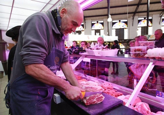 Un carnicero atiende a sus clientes desde su puesto del Mercado Central.