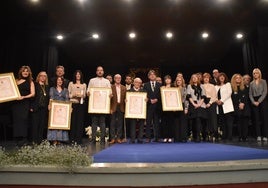 Imagen de galardonados y familiares en el escenario del teatro Cervantes tras recibir las distinciones del Ayuntamiento de Béjar