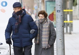 Dos personas mayores pasean bien abrigadas por las calles de Salamanca.