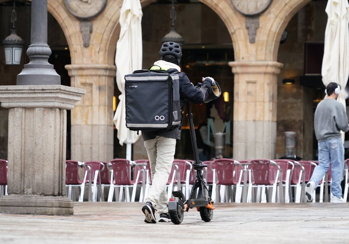 Un conductor de patinete, caminando por la Plaza Mayor de Salamanca.