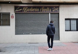 Un joven, ajeno a esta información, frente a la barbería regentada por uno de los detenidos en Garrido.