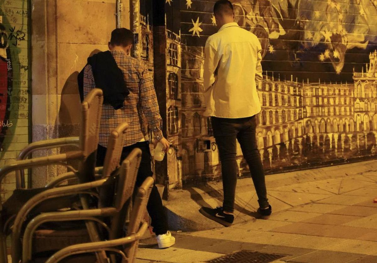 Dos jóvenes orinan contra la fachada de un edificio del centro de Salamanca.