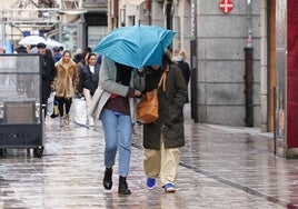 Ciudadanos se protegen de la lluvia por las calles de Salamanca.