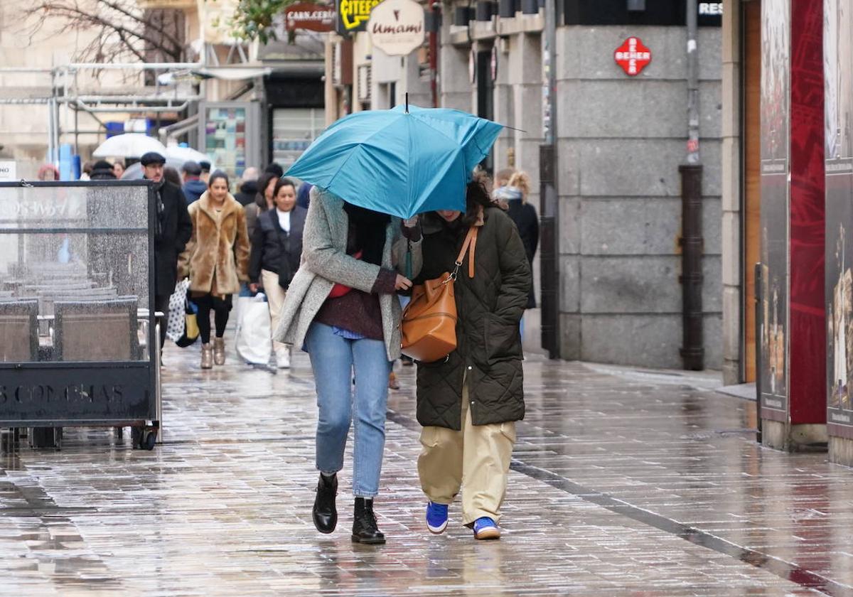 Ciudadanos se protegen de la lluvia por las calles de Salamanca.