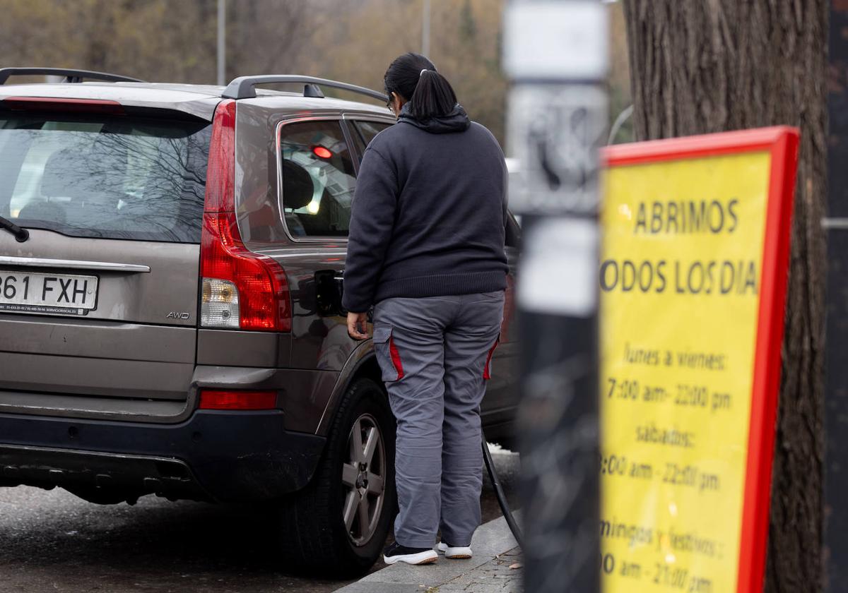 Una mujer llenando el depósito de su vehículo en una gasolinera.