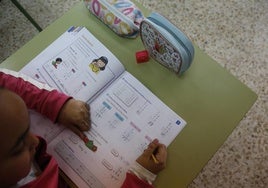 Una niña aprendiendo realizando ejercicios de matemáticas en un libro de texto.