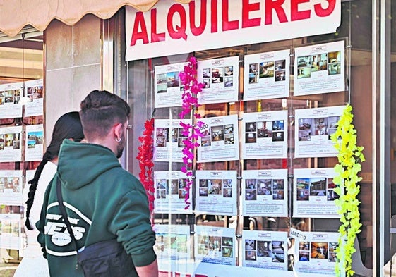 Dos jóvenes mirando anuncios de pisos de alquiler.