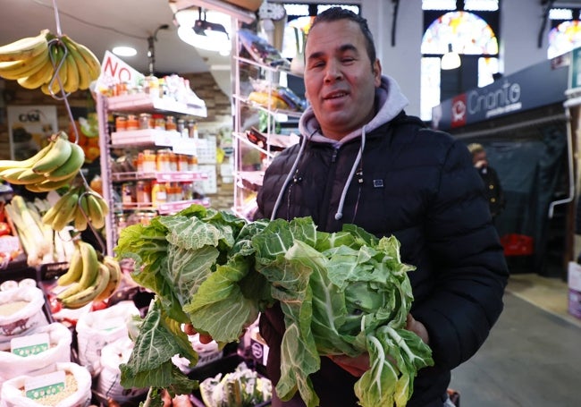 Un comerciante del Mercado sostiene unas berzas.