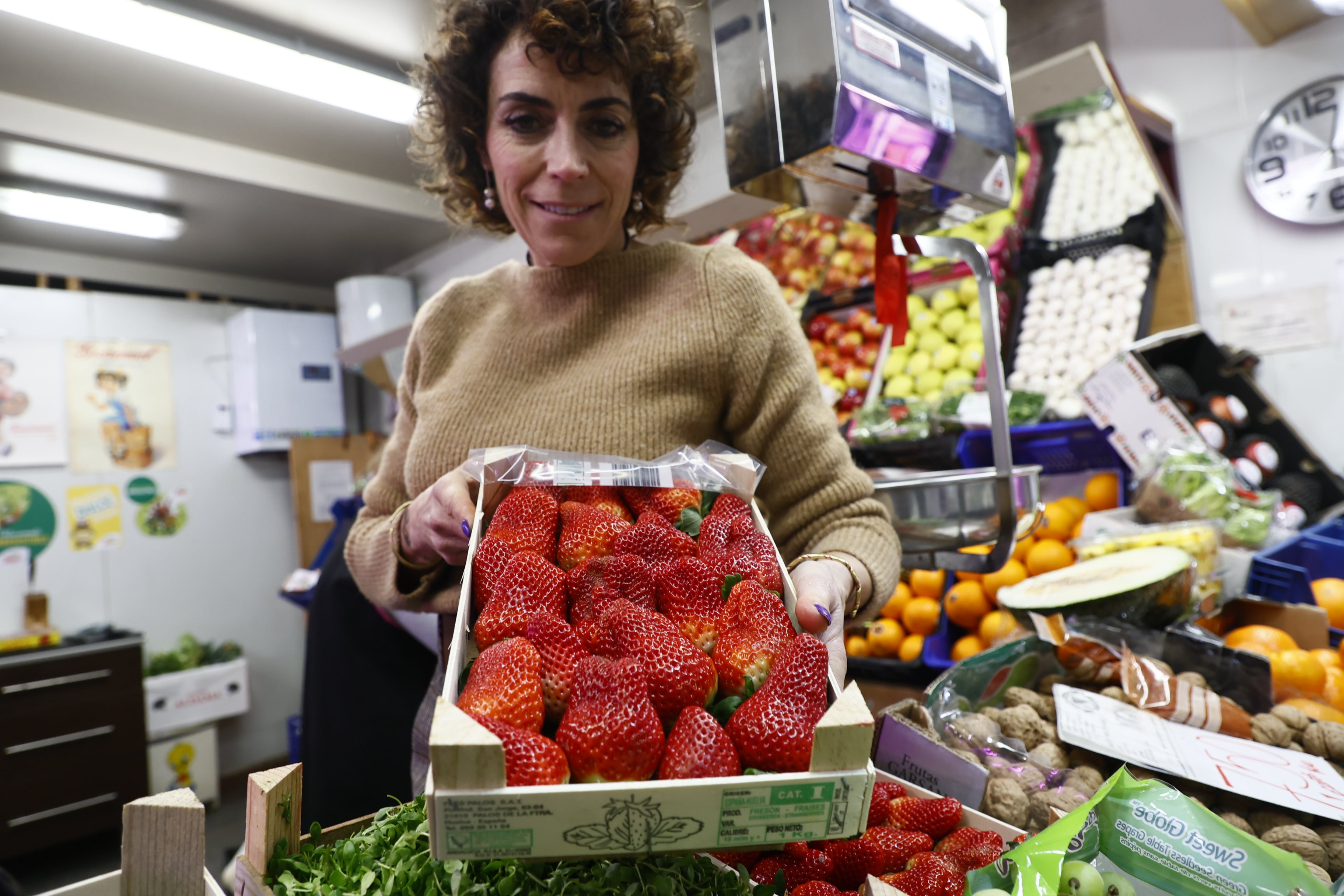 Susana, una frutera del Mercado, sostiene una caja de fresas.