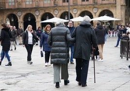 Dos personas mayores paseando por la Plaza Mayor.