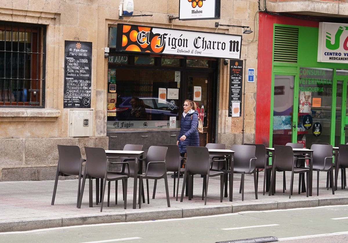 Una mujer pasa junto a una terraza de la calle Van Dyck.