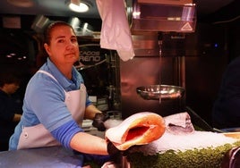 Una pescadera del Mercado Central sostiene un salmón y un bacalao.