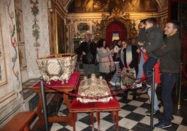 Las familias, alzando a los niños en el camarín alto de la iglesia basílica de la Anunciación, para que pudiesen ver el interior de la urna de plata de Santa Teresa