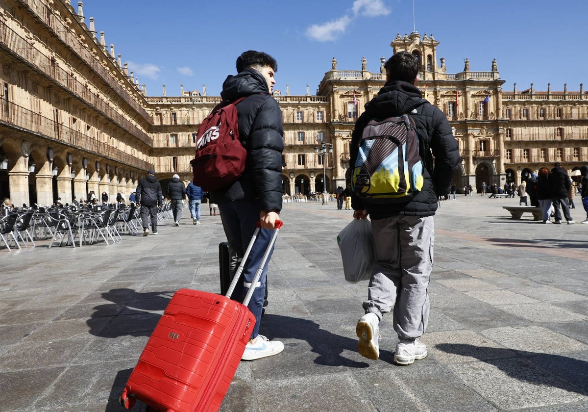 Dos jóvenes con mochilas y maletas por la Plaza Mayor.