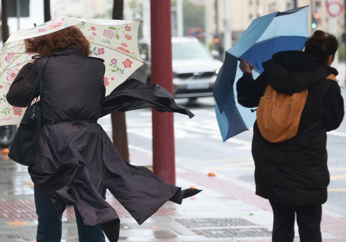 Personas sufren la llegada de una borrasca con viento y lluvia.