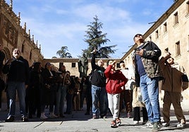 Un grupo de turistas en el patio de Escuelas Mayores busca la rana de la fachada de la Universidad.
