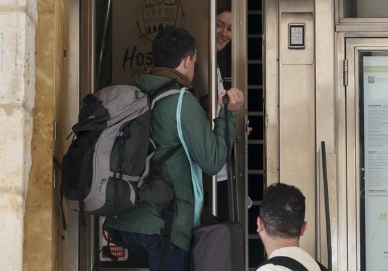 Clientes entran en un alojamiento de la ciudad con sus mochilas y maletas.
